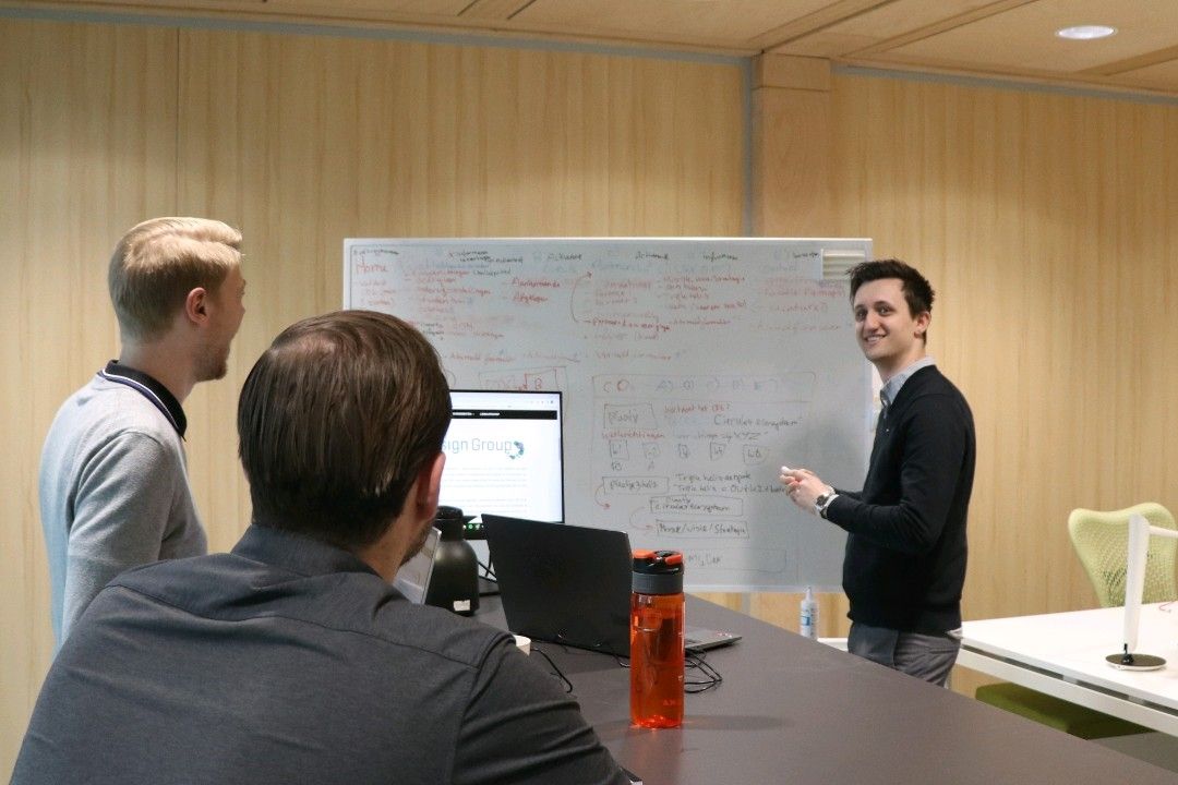 Drie mensen aan een volgeschreven whiteboard tijdens een werksessie
